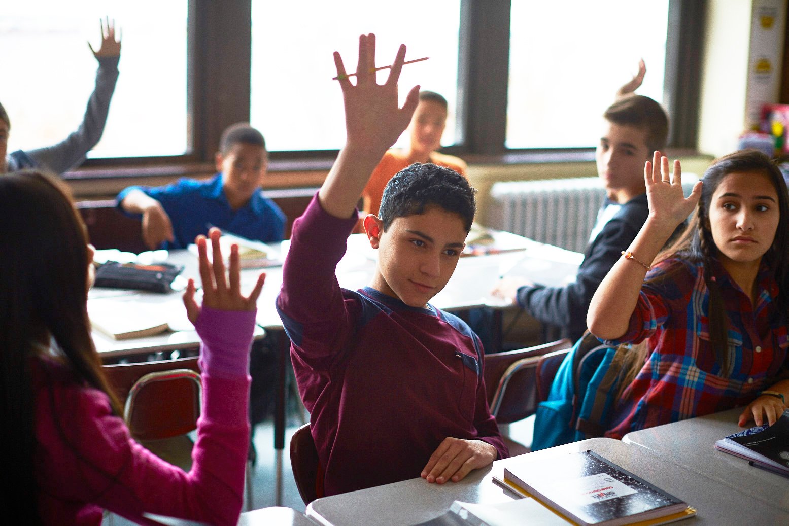 Students raising hands in class.