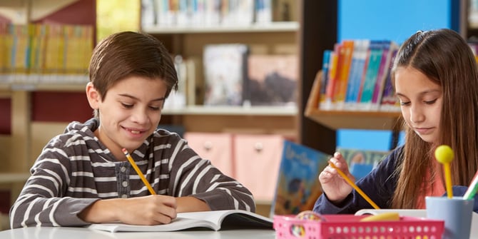 Students working in a classroom and writing in books.