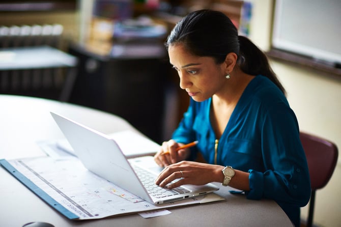 A teacher planning for a year of math learning with Eureka Math Squared at her desk on a computer with a calendar. 