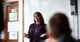 Female teacher standing in the front of a room presenting.